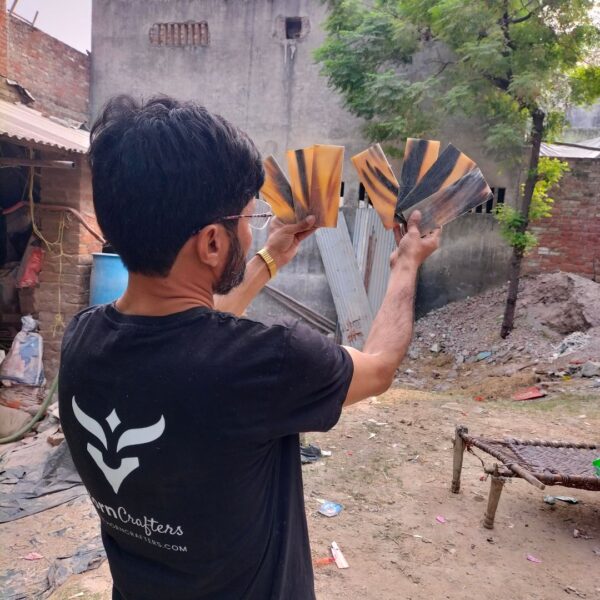 Buffalo horn plates in hands of horn crafter's team member with trees in background